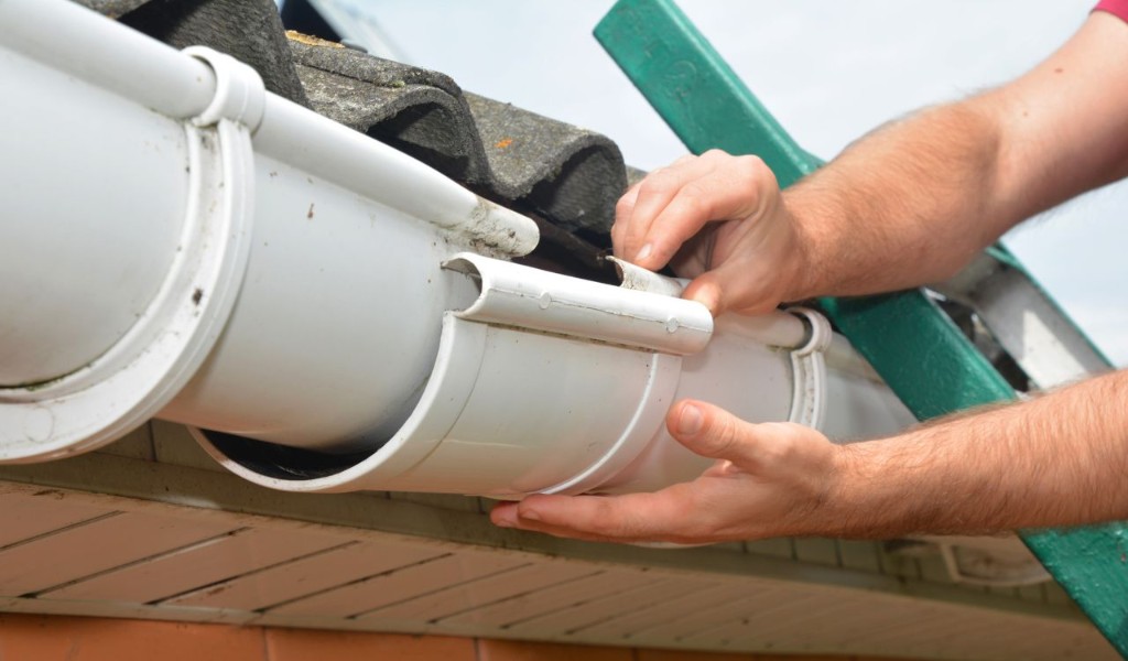 Hands joining white gutter sections during a South Florida repair