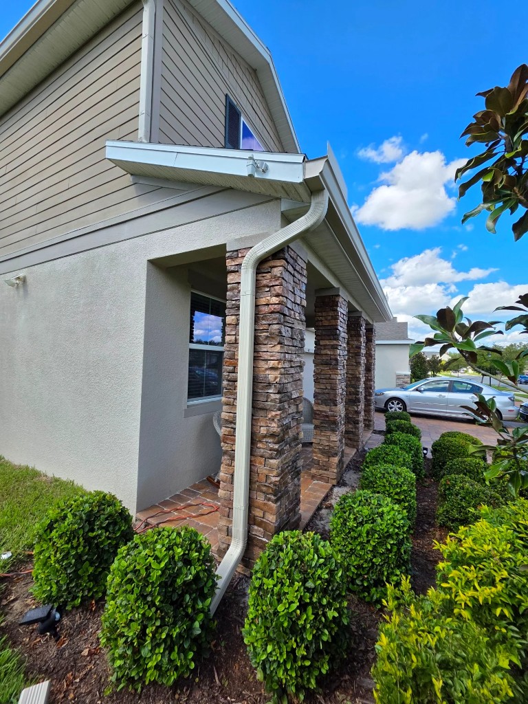 White seamless gutters and downspout on a stone-column South Florida home
