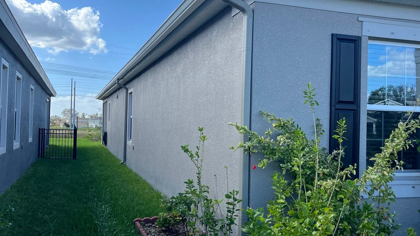 Single-story ranch with new gutters draining toward underground piping in Tampa